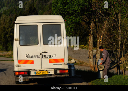 Uomo che porta full metal Bidoni del latte nel suo carrello vicino al villaggio di Hauteluce nella regione di Beaufortain, sulle Alpi francesi, Savoie, Europa Foto Stock