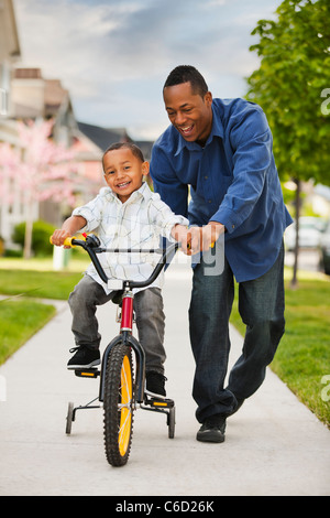 Padre figlio di insegnamento per guidare la bicicletta Foto Stock