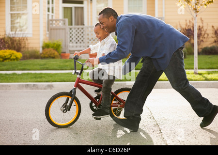 Padre figlio di insegnamento per guidare la bicicletta Foto Stock