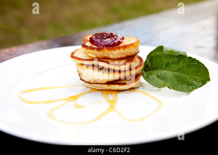 Frittelle su una piastra ricoperta con marmellata e sciroppo d'acero con la menta sul lato Foto Stock