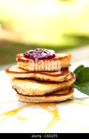 Frittelle su una piastra ricoperta con marmellata e sciroppo d'acero con la menta sul lato Foto Stock