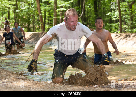 Un robusto Mudder partecipante corre attraverso il 'Swamp Stomp'' sezione del corso. Mudder resistente è una giornata di sport estremi Foto Stock