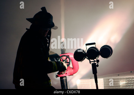 Fireman usando un cannone a combattere un incendio notturno in New Jersey Foto Stock