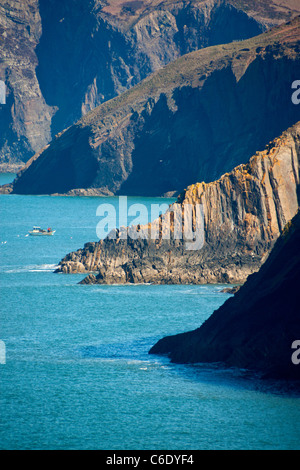 Scogliere sulla costa guardando da Ceibwr Bay a Pen yr Afr con barca da pesca in cove Pembrokeshire West Wales UK Foto Stock