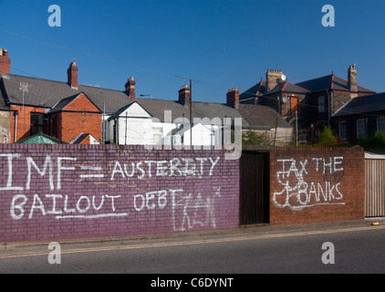 Graffiti politico per condannare la politica economica FMI = Salvataggio di austerità fiscale Debito le banche vernice bianco su rosso e parete di mattoni Foto Stock