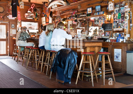 La gente seduta a riccamente intagliati in legno vintage bar decorato con memorabilia sportivi nella vecchia taverna Coupeville Washington Foto Stock