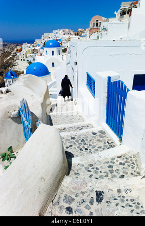 Grecia Cicladi, Santorini, Oia, Donna che cammina verso il basso passi in città Foto Stock