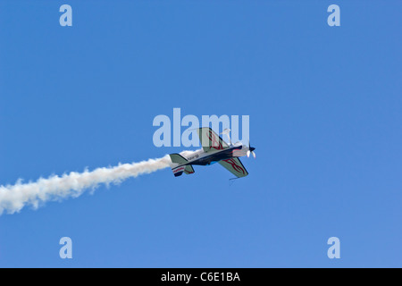 Unico invertito piano Stunt aeromobile con fumo trail eseguendo acrobazie display nel cielo azzurro capovolto capovolto Foto Stock