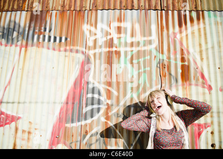 Stati Uniti d'America, Brooklyn, Williamsburg, ritratto di donna con le cuffie contro il muro di graffiti Foto Stock