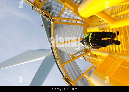 Un ingegnere che si arrampica su un pezzo di transizione di una turbina eolica sulla Walney offshore wind farm, Foto Stock