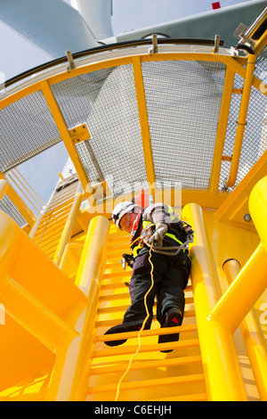 Un ingegnere che si arrampica su un pezzo di transizione di una turbina eolica sulla Walney offshore wind farm, Foto Stock