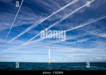 Contrails su turbine eoliche in Walney offshore wind farm. Foto Stock