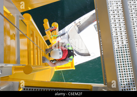 Un operaio si arrampica su una turbina, al Walney offshore wind farm Foto Stock