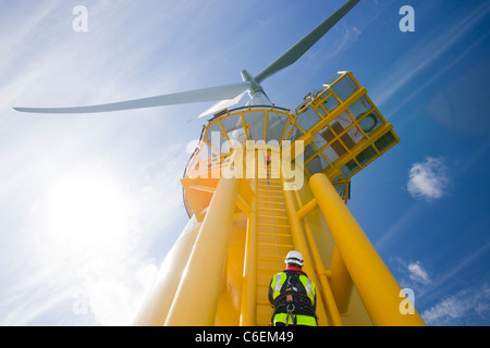 Un operaio si arrampica su una turbina, al Walney offshore wind farm Foto Stock