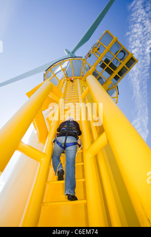 Un operaio si arrampica su una turbina, al Walney offshore wind farm Foto Stock