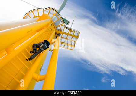 Un operaio si arrampica su una turbina, al Walney offshore wind farm Foto Stock