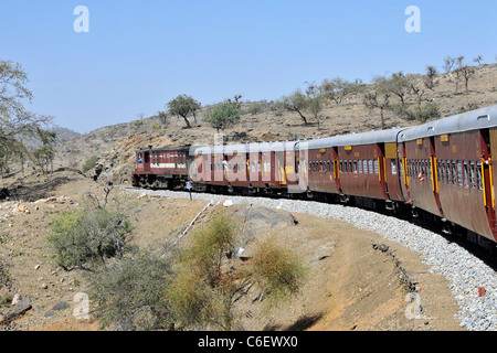 Treni passeggeri passando attraverso le gamme Aravalli Rajasthan in India Foto Stock