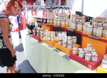 Donna che guarda in barattoli di miele sul mercato in Gordes town, dipartimento di Vaucluse nella regione della Provenza, Francia Foto Stock