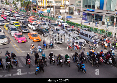 Motociclette e auto attendere al semaforo in corrispondenza della giunzione di Thanon Asok Montri road con Sukhumvit road nel centro di Bangkok Foto Stock