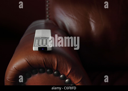 Telecomando TV posizionato sul braccio di un comodo divano in pelle Foto Stock