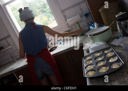 Un 15-anno vecchio adolescente cuoce party torte in una cucina domestica. Foto Stock