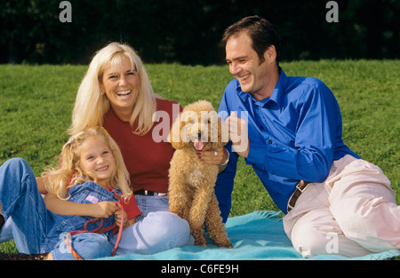 Famiglia con cane barboncino su prato Foto Stock