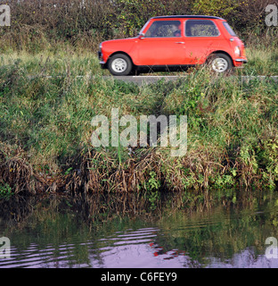 Un rosso Austin Mini viaggiando lungo una strada di campagna a fianco del canale di Nottingham, offuscata al di fuori della messa a fuoco come velocità. Foto Stock