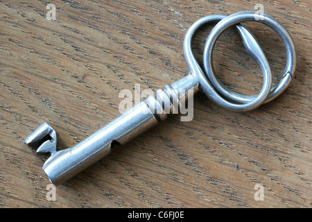 Close up di argento antico sulla chiave in legno di noce in background Foto Stock