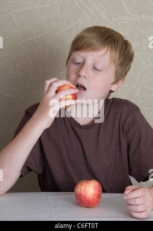 Un dodicenne ragazzo di mangiare un Apple Foto Stock