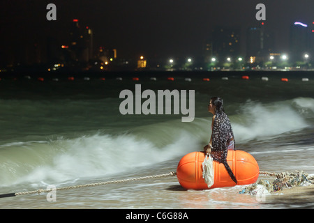 Thai donna seduta sulla grande boa in Pattaya Beach di notte, Pattaya , Thailandia Foto Stock