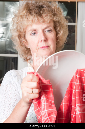 Donna di lavaggio e di essiccamento facendo lavori domestici in cucina Foto Stock