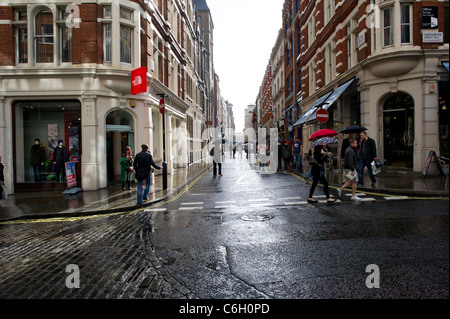 Un estate doccia a pioggia cade sul shopper in Covent Garden di Londra. Foto Stock
