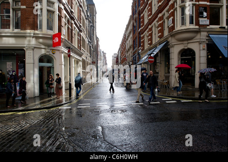 Un estate doccia a pioggia cade sul shopper in Covent Garden di Londra. Foto Stock