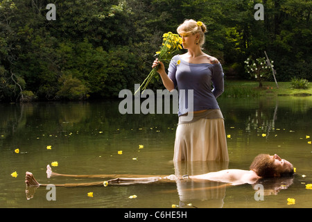 Donna che mantiene i fiori in piedi su floating man - Cedar Mountain, North Carolina, STATI UNITI D'AMERICA Foto Stock