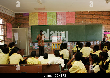 I bambini della scuola elementare che viene insegnata da un insegnante in una classe Foto Stock