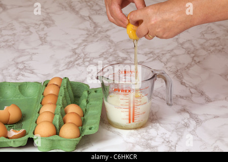 Una donna è vista rompere un uovo nel latte; con lo spazio per il testo Foto Stock