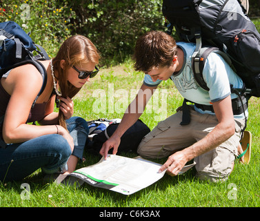 Una giovane coppia con lo zaino in spalla, backpackers, la lettura e lo studio di una mappa. Northland e North Island, Nuova Zelanda Foto Stock