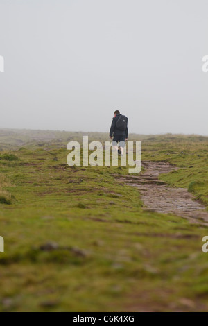 Un camminatore solitario ascende Pen-y-ventola in Brecon Beacons sotto basse nubi Foto Stock