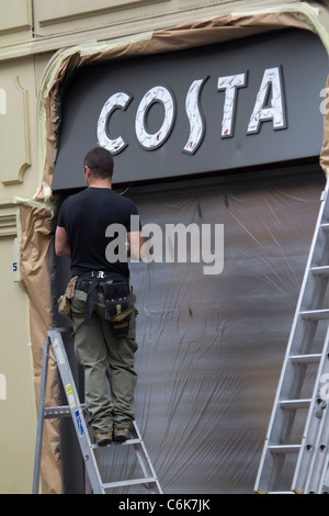 workman on Stepladder presenta un nuovo cartello con la caffetteria Costa di Whitbread, nel centro di Londra, nel Regno Unito. Foto Stock