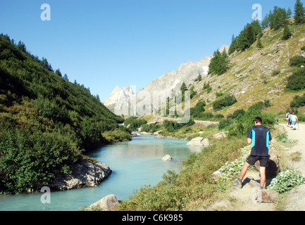 Un fiume scorre attraverso una ripida Valle nelle alpi vicino a Mont Blanc con le montagne del Col Ferret in background Foto Stock