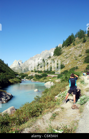 Un fiume scorre attraverso una ripida Valle nelle alpi vicino a Mont Blanc con le montagne del Col Ferret in background Foto Stock