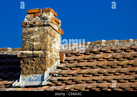 Vecchia ciminiera in mattoni e tetto con un cielo luminoso sullo sfondo Foto Stock