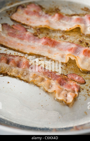 La cottura di pancetta affumicata in padella Foto Stock