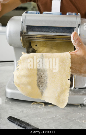 Il rotolamento pasta attraverso la macchina per la pasta per fare i fogli di pasta Foto Stock