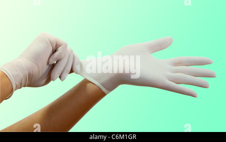 Donna mettendo mano su guanti chirurgici,illuminazione specifica per il funzionamento la camera. Foto Stock