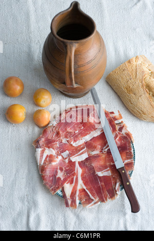 Piatto di prosciutto tagliato con i pomodorini e la pagnotta di pane Foto Stock