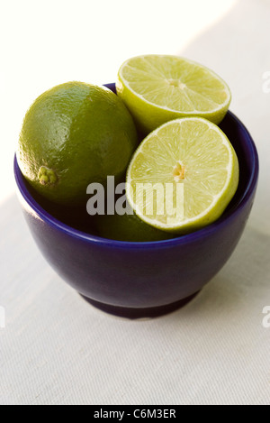 Limes, intero e dimezzato nel recipiente Foto Stock