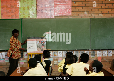 I bambini della scuola elementare che viene insegnata da un insegnante in una classe Foto Stock