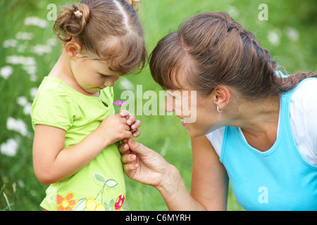 Giovane madre premurosa comfort una bambina in un prato Foto Stock