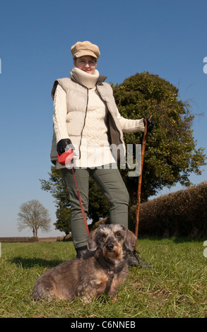 Una giovane donna camminare un bassotto cane al guinzaglio in campagna Foto Stock